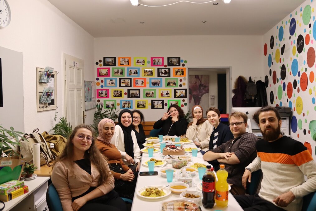 A group of volunteers sit around a table with food on their plates.